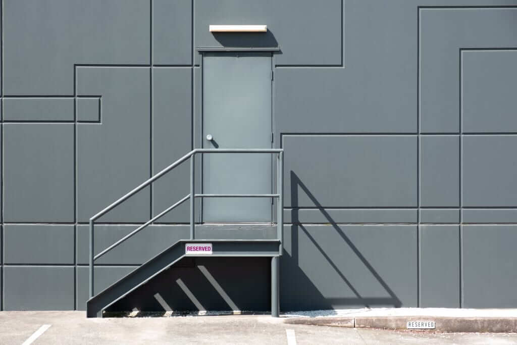 Rear,Entrance,Door,With,Metal,Stairs,Into,Industrial,Building,-