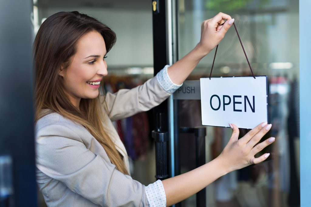 Woman hanging open sign on glass door