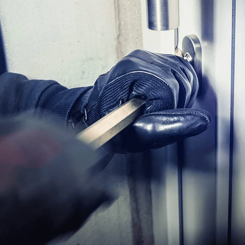 Burglar opening commercial door with crowbar