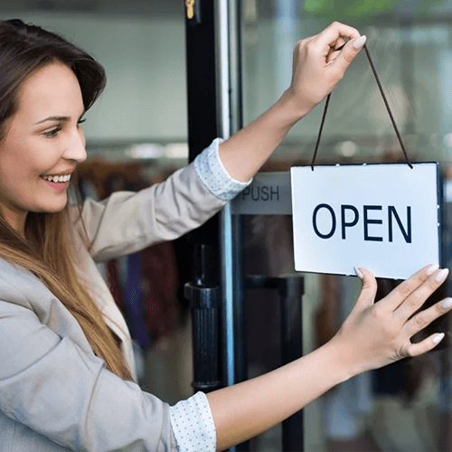 Woman hanging open sign on glass door